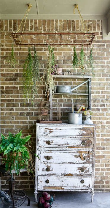 The perfect plant drying rack for your patio. If you want a French country feel on your porch then a vintage baby mattress spring is the best idea! Maybe you can even use it for a herb drying rack if you are a foodie! #herbdryingrack #diydryingrack #wildflowers #herbdrying #cozyporch #porchquilt
