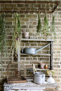 The perfect plant drying rack for your patio. If you want a French country feel on your porch then a vintage baby mattress spring is the best idea! Maybe you can even use it for a herb drying rack if you are a foodie! #herbdryingrack #diydryingrack #babybedidea#wildflowers #herbdrying #cozyporch #porchquilt