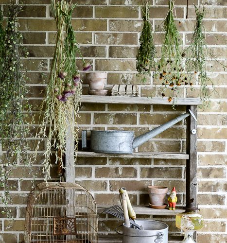 The perfect plant drying rack for your patio. If you want a French country feel on your porch then a vintage baby mattress spring is the best idea! Maybe you can even use it for a herb drying rack if you are a foodie! #herbdryingrack #diydryingrack #babybedidea#wildflowers #herbdrying #cozyporch #porchquilt