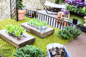 Tour a miniature vintage garden shop dollhouse for great ideas for your own dollhouse decor. See how to make a cozy home, lush garden and outdoor miniature yard! COmplete with garden gnomes, miniature potted plants and sitting areas. #dollhouse #miniatures #DIYdollhouse #vintagegarden #tinydecor