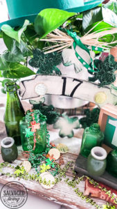 St. Patrick's Day decor ideas from the Dollar store. Use this cute St. Patrick's day wreath tutorial and St. Patrick's Day home decor styling idea to create a cute green space in your home! Mix old, vintage items with dollar store decor for a classic St. Paddy's day look. #stpatricksday #dollarstorecraft #budgetdecoridea