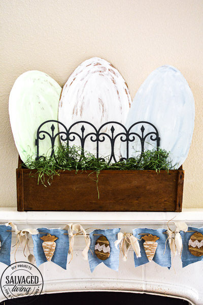 Decorate your mantle for Easter with this budget Easter mantle decorating idea from cardboard! Seriously the best budget decorating hack there is , so easy and you can paint it any color or style. Also tips to make an Easter banner from dollar store items and things you have on hand at home already. #budgetdecor #eastermantle #easterdecoratingideas #dollarstorecraft #dollartreedecor