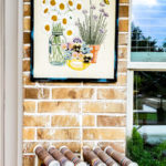 Learn how to hang pictures on brick wall easily with this step by step tutorial. Haning pictures on brick is easy with the right tools and can make your outdoor living space feel like a cozy room in your home. #howtotip #decoratinghack #patiodecoridea