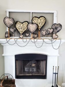 Learn how to make gorgeous giant paper hearts for Valentine's Day decorating on repurposed spindle stands. This dollar store craft is perfect for a farmhouse Valentine theme. #vintageValentine #upcycledprojectidea #spindle #papercraft #stencilart #valentinesdaymantel