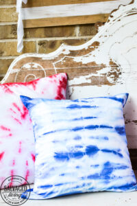 Create easy tie dye pillows with Testors fabric spray paint. This less mess tie-dye technique is so much easier than traditional tie-dye and gives you the same effect. This fabric paint dries soft and looks amazing for your holiday decor and pillows. Try this easy fabric craft for a multitude of craft ideas. #testors #testorscraft #crafttherapy #tiedye #fabricpainting #pillow #tiedyemethod #tiedyetechnique