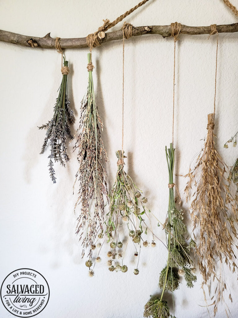 Make a stunning wall hanging from dried flowers and dried grasses for you a boho chic wall hanging in your home. This simple DIY is budget-friendly decor at it's finest! #wallart #driedflowers #bohodecor #farmhousewallart 