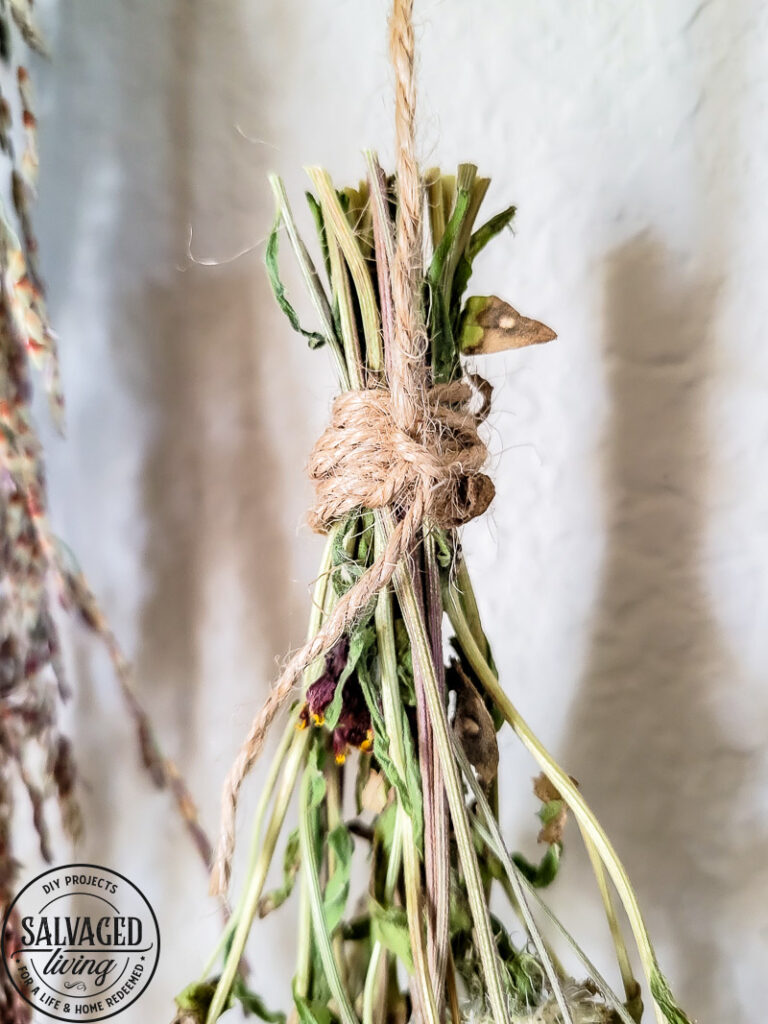 Make a stunning wall hanging from dried flowers and dried grasses for you a boho chic wall hanging in your home. This simple DIY is budget-friendly decor at it's finest! #wallart #driedflowers #bohodecor #farmhousewallart 