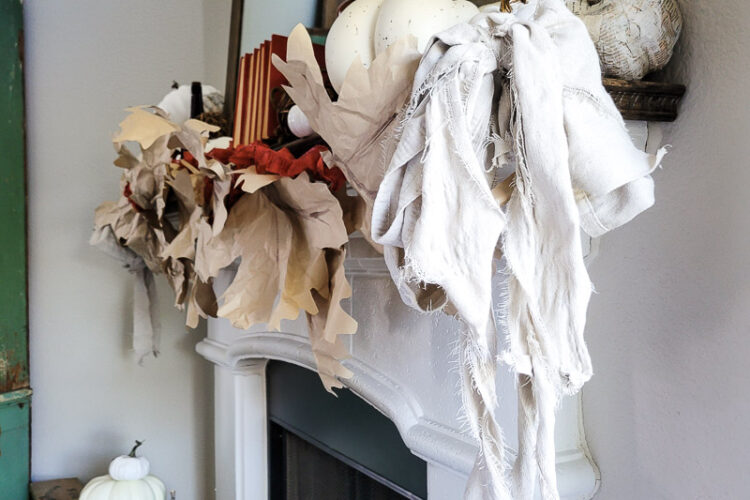 Learn how to make DIY giant paper leaf garland for your fall mantel or fall decorating. This budget garland idea is perfect to add a warm touch of fall to your home and the tutorial is so easy! Mix in some white pumpkin decor, gathered ribbon garland and cozy books for a cozy fall decor idea! #fallvibe #papergarland #papercraft
