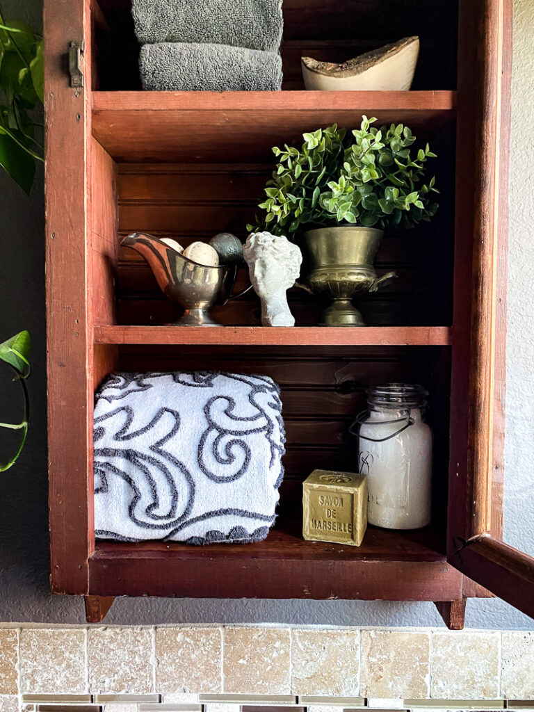 a thrifted cabinet found at a garages sale is perfect for a cozy bathroom upgrade, come see how I decorated this garage sale cabinet for function and style. #bathroomdecor #vintagebathroomstyle #cozybathroom