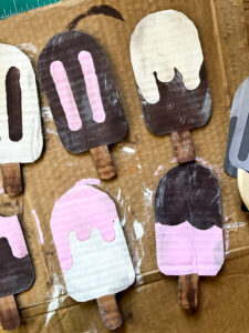 Adorable popsicle decor for your summer decorating enjoyment right here! These no mess popsicles are the perfect way to add some childhood fun to your adult vintage home. Made to look like vintage style signs, these popsicles crafted from cardboard are not only easy and fun to make, but a cheap decor idea! Use your own color shceme to make them fit your decorating style. Would be great 4th of July decor as well! #summerdecor #cardboardcraft #DIYgarland